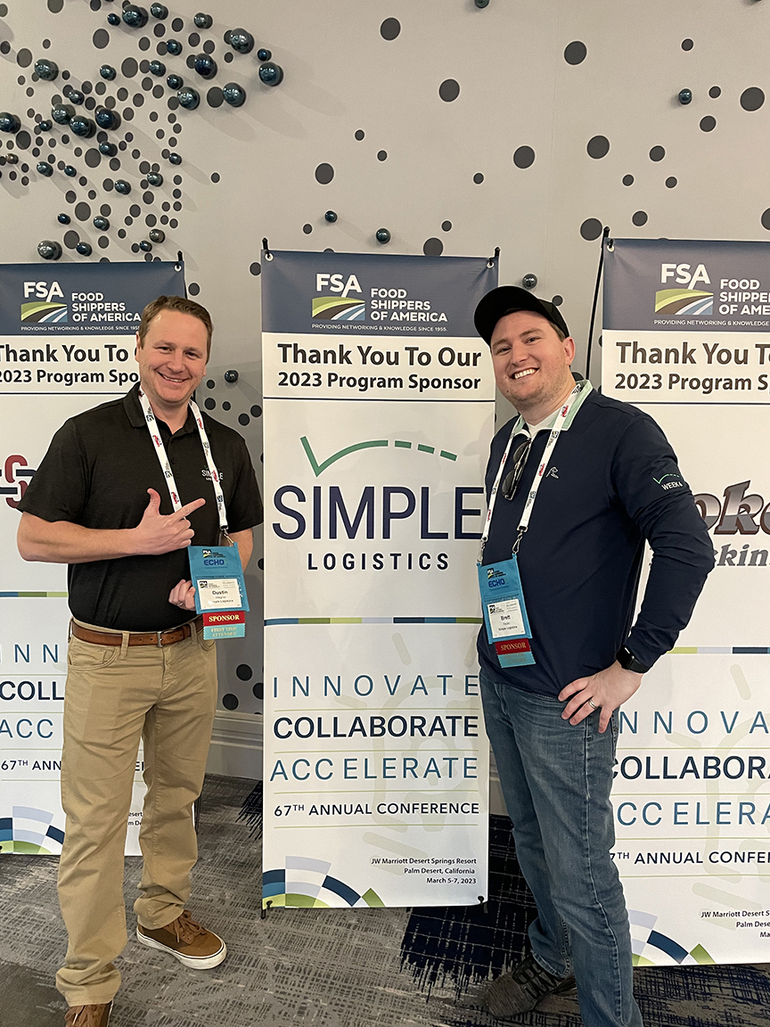Dustin and Brett standing in front of a Simple Logistics sponsorship banner at the FSA Conference