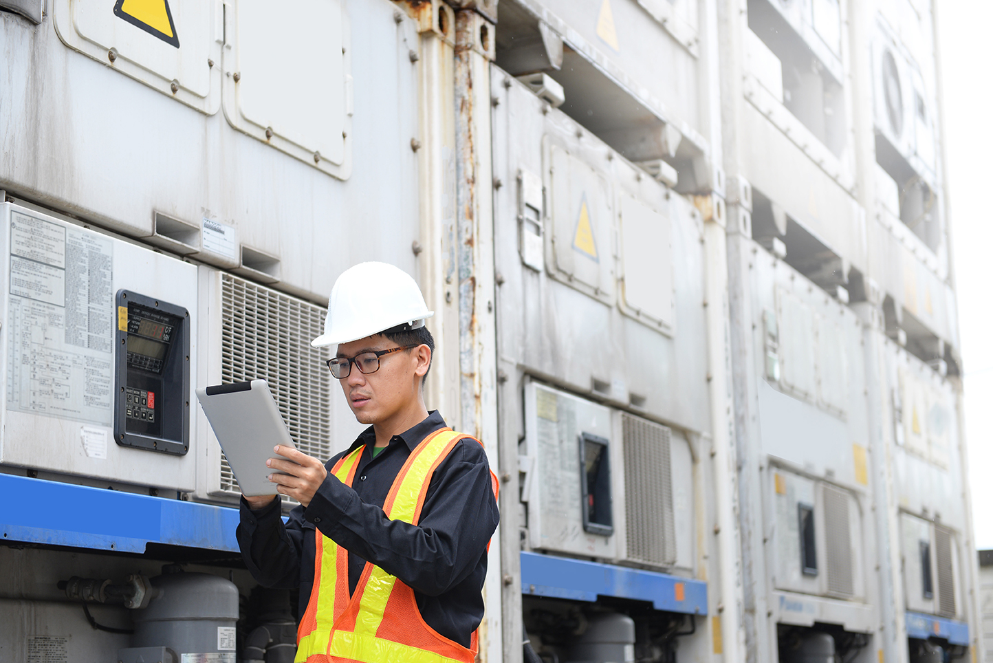 Reefer container technician is using tablet for monitoring temperature-controlled cold shipments