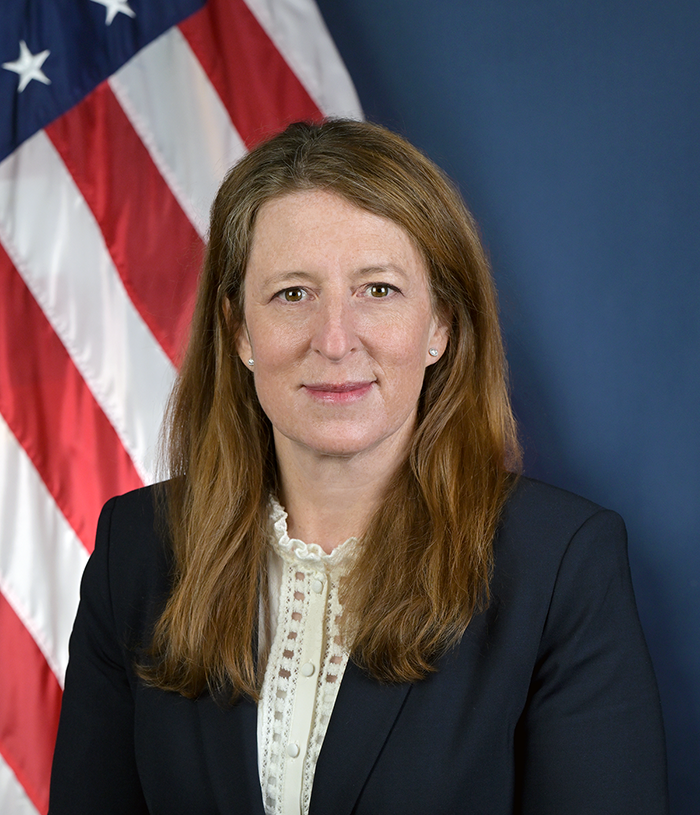Portrait of Robin Hutcheson, administrator for FMCSA in front of blue background and American Flag